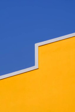 Klasik sarı bina duvarının soyut mimari arka plan tasarımı mavi berrak gökyüzüne karşı minimal stil ve dikey çerçeve