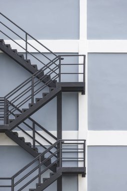 Dikey çerçeveli gri ve beyaz bina duvarındaki siyah çelik yangın çıkışının arka planı