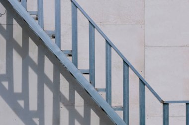 Çelik balyaların dışında, bina inşaatında arka planda gri tahta üzerinde merdiven yapısı var.