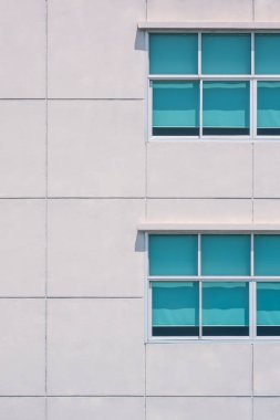 Ofis binasının büyük kare beton duvarında dikey çerçevede 2 sıra cam pencere.