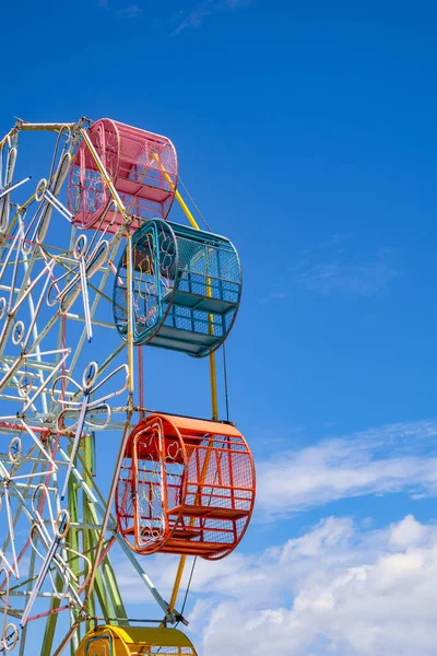 Part of the old colorful Ferris wheel with fluorescent lamp decoration against cloud on blue sky background in vertical frame