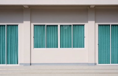 Bej ofis binasının içinde mavi perdeli cam sürgülü kapı ve pencerelerin ön görüntüsü