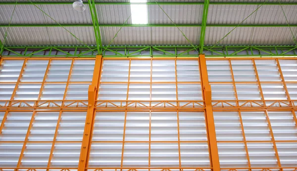 View from below of aluminum louver wall with metal roof structure inside of modern warehouse building