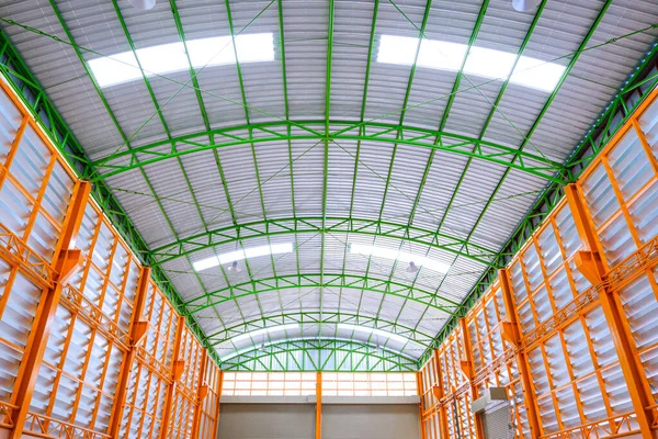 Symmetry and low angle view of aluminum louver wall with metal roof structure inside of large modern industrial building
