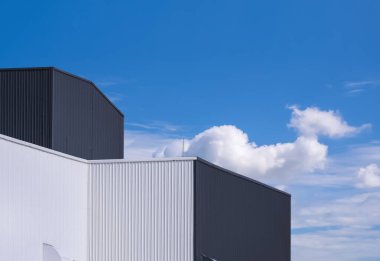 Mavi gökyüzü arka planına karşı siyah-beyaz kıvrımlı metal fabrika binalarının düşük açılı görüntüsü