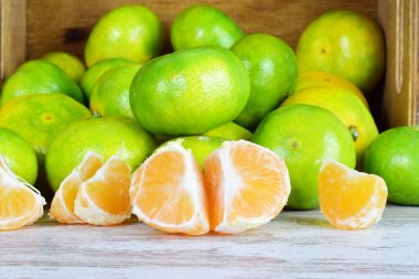 Ahşap bir masanın üstünde, soyulmuş mandalina ve tüm yeşil deri parçaları..