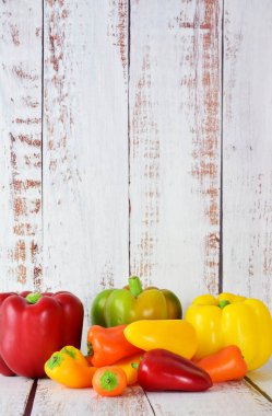 Biberler, renkler ve boyutlar, açık renkli ahşap arka plan. Boşluğu kopyala.