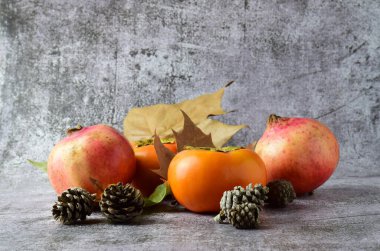 Sonbahar meyvesi, hurma ve nar, yapraklar ve ananas dağınık dış hatlar ve taş zemin. Boşluğu kopyala.