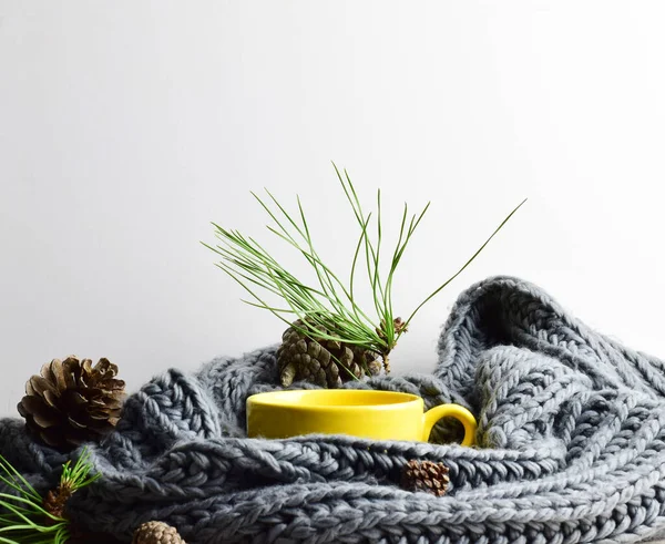 Yellow mug, on woolen cloth, pine cones in outline, season, winter concept. Copy space.