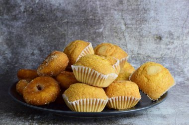 Şekerli çörekler ve çörekler taş zeminde koyu bir tabakta..