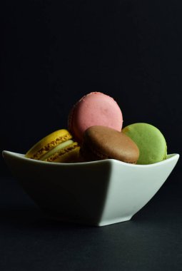 Makaronlar, siyah arka planda izole edilmiş, tipik Fransız tatlısı. Boşluğu ve dikey görüntüyü kopyala.