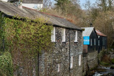 Blue bike shop sign on an old wooden building overlooking a stream in Ambleside, Cumbria, UK