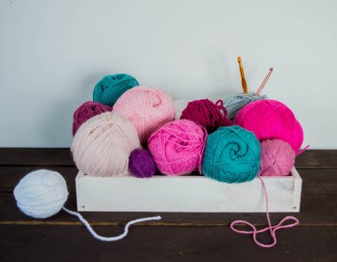 Koyu kahverengi ahşap zeminde el yapımı renkli yün toplar.