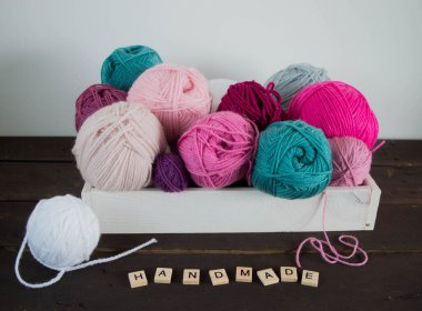 Koyu kahverengi ahşap zeminde el yapımı renkli yün toplar.