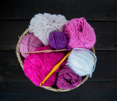 Koyu kahverengi ahşap zeminde el yapımı renkli yün toplar.