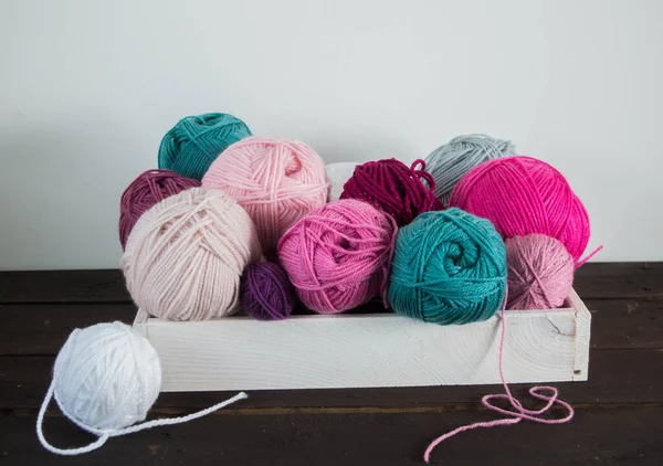 Koyu kahverengi ahşap zeminde el yapımı renkli yün toplar.