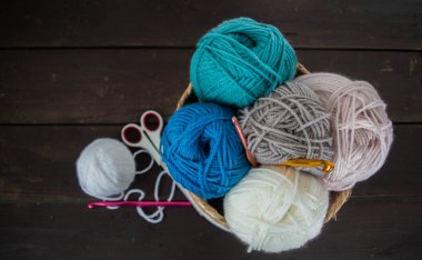 Koyu kahverengi ahşap zeminde el yapımı renkli yün toplar.