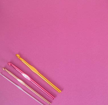 Pembe örgü üzerinde renkli kancalar.