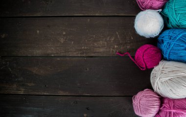 Koyu kahverengi ahşap zeminde el yapımı renkli yün toplar.