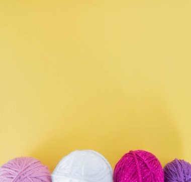 Sarı zemin üzerinde renkli yün toplar.