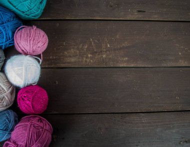 Koyu kahverengi ahşap zeminde el yapımı renkli yün toplar.