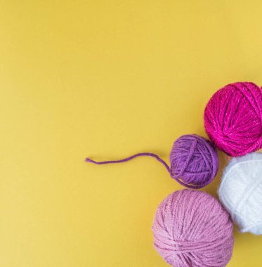 Sarı zemin üzerinde renkli yün toplar.