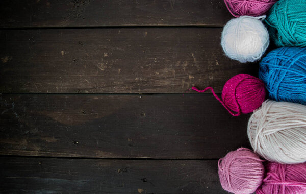 colorful woolen balls on dark brown wooden ground for handicrafts handmade