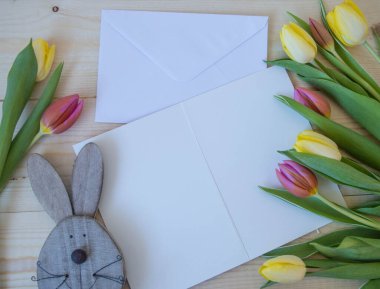 Beyaz kart ve zarf ahşap zemin üzerinde, yazı için yeri olan laleler.