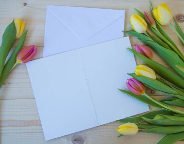 Beyaz kart ve zarf ahşap zemin üzerinde, yazı için yeri olan laleler.