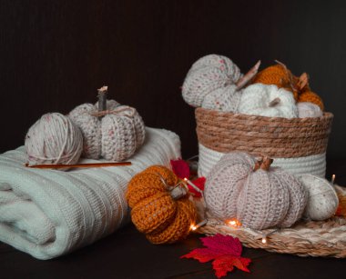 Sonbahar yapraklı el yapımı beyaz, bej ve sarı el yapımı balkabakları, tığ işi kanca, koyu kahverengi ahşap zemin üzerinde yün toplar