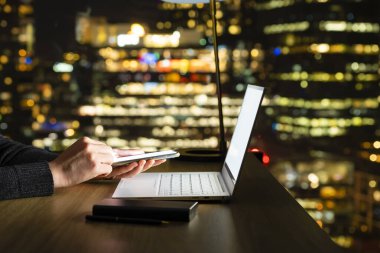 Odak şehir ufuk çizgisi arkaplanı olmadan, gece akıllı telefon kullanmak