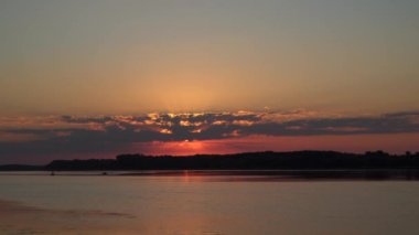 Nehrin üzerinde muhteşem bir gün batımı. Güneş ışınları bulutların arasından geçiyor, kameranın önünde bir kuş uçuyor, bir teknede balıkçıları görebilirsiniz.