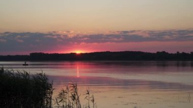 Dinyeper Nehri Ukrayna. Nehrin üzerinde gün batımını canlandırın. Nehirde kayıkta bir balıkçı görebilirsiniz.