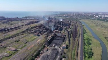 Metalürjik bitki kuş bakışı. Çelik fabrikası nehrin kıyısında, ufukta deniz var.