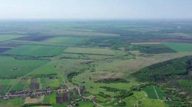 İnsansız hava aracı bakış açısı. Bahar tarlaları ve yol kenarında bir köy.