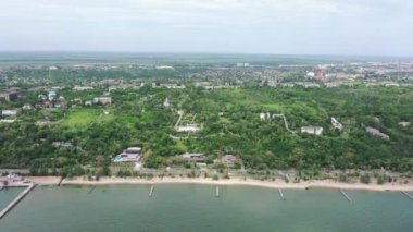 Deniz kenarındaki şehrin panoramik manzarası kuş bakışı. Birçok bina ağaçların arasında yer almaktadır. Mariupol Ukrayna