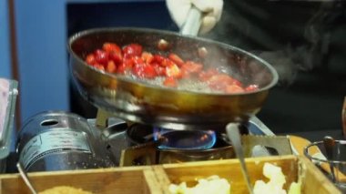 Şef çilekleri ateşte kızartıyor ve tavaya fırlatıyor. Yavaş çekim.