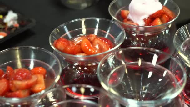 Chef pose la crème glacée dans des bols en verre avec des fraises — Video