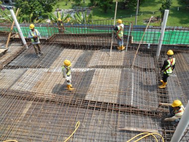 MALACCA, MALAYSIA -16 Mayıs 2016: Malezya 'daki inşaat alanında çelik takviye barı üreten inşaat işçileri. Destek çubuğu küçük bir kabloyla birbirine bağlanmış.. 
