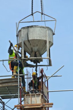 JOHOR, MALAYSIA - MAYIS 06, 2016: İnşaat alanındaki sütun biçimlerine beton kova kullanarak beton döken bir grup inşaat işçisi.  