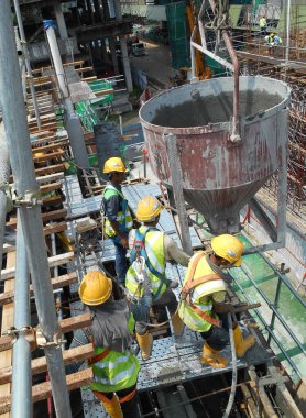 JOHOR, MALAYSIA - MAYIS 06, 2016: İnşaat alanındaki sütun biçimlerine beton kova kullanarak beton döken bir grup inşaat işçisi.  