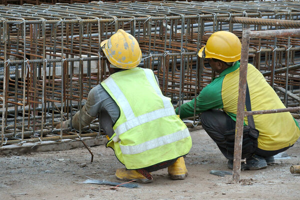 MALACCA, MALAYSIA -MAY 16, 2016: Construction workers fabricating steel reinforcement bar at the construction site in Malacca, Malaysia. The reinforcement bar was tied together using the tiny wire. 