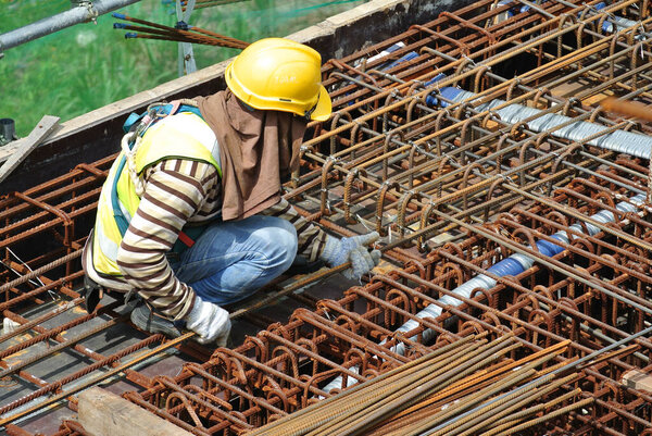 MALACCA, MALAYSIA -MAY 16, 2016: Construction workers fabricating steel reinforcement bar at the construction site in Malacca, Malaysia. The reinforcement bar was tied together using the tiny wire. 