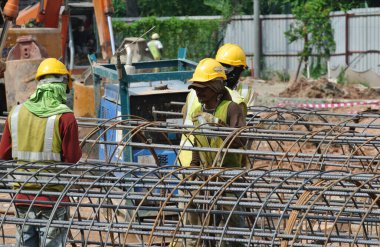 MALACCA, MALAYSIA -16 Mayıs 2016: Malezya 'daki inşaat alanında çelik takviye barı üreten inşaat işçileri. Destek çubuğu küçük bir kabloyla birbirine bağlanmış..