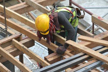 PERAK, MALAYSIA -10 Nisan 2016: Perak, Malezya 'daki şantiyede kereste ve kontrplak kullanarak ahşap döşeyen inşaat işçileri.  