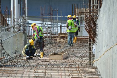 MALACCA, MALAYSIA -16 Mayıs 2016: Malezya 'daki inşaat alanında çelik takviye barı üreten inşaat işçileri. Destek çubuğu küçük bir kabloyla birbirine bağlanmış..