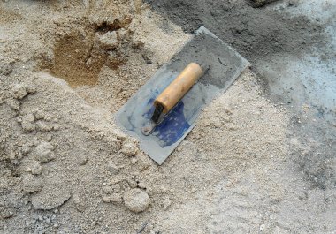 İnşaat alanındaki kumun üzerine sıva yapmak için çimento malası kullanılıyor. 