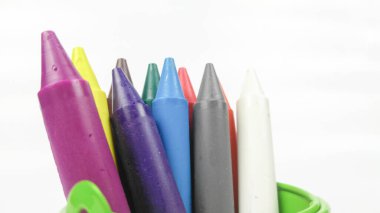 Renkli çocuklar, beyaz arka planda izole edilmiş yeşil kovada boya çubukları..  