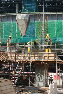 SELANGOR, MALAYSIA 12 ARALIK 2015: İnşaat alanındaki kiriş biçimine beton kova kullanarak beton döken bir grup inşaat işçisi. 