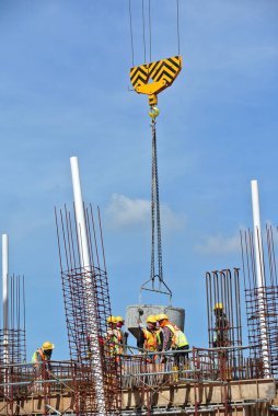 SELANGOR, MALAYSIA 12 Aralık 2015: İnşaat alanındaki kereste formuna beton kova kullanarak ıslak beton döken bir grup inşaat işçisi.  